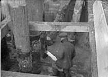 Industrial District, British Forgings Ltd. sawing off bearing piles in coffer-dam Toronto, Ont. Mar. 3, 1917