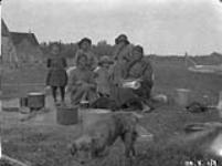 Two Cree women with four children and puppies. August 1926.