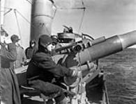 Unidentified personnel manning a four-inch gun aboard H.M.C.S. ST CROIX at sea, March 1941. March 1941.
