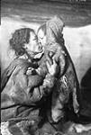 [Padluk with one of her four children at Pipkaknak's camp southwest of Padlei, N.W.T.].  

  [ca. February 1950].