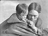 (Femme Padleimiut donnant du caribou à un enfant dans un camp près de Padlei, T.N.-O.) [Kinaryuak (à gauche) et Kipsiyak (à droite).] [Février 1950]