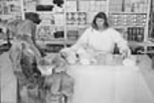 Inuit trading furs for food supplies. [Le caissier s'appelait Henry. Sur la photo, il est en train de négocier avec une autre personne l'échange de fourrures de renards contre des produits alimentaires.] 1949-1950