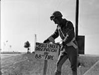 Lance-Corporal Peter Chimilar, Canadian Provost Corps (C.P.C.), placing a warning sign on the roadside, Hautmesnil, France, 14 August 1944. August 14, 1944