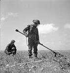 Spr. G. Tennant (Hamilton, ON) with mine detector and Spr. D. Fulton (Meadow Lake, SK), Royal Canadian Engineers (R.C.E.), 9th Canadian Infantry Brigade, Normandy, France, 22 June 1944. June 22, 1944.