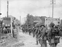 Infantrymen of Le Régiment de la Chaudière moving through Bernières-sur-Mer, France, 6 June 1944. June 6, 1944.