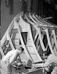 Workers notching a frame of a motor torpedo boat under construction at Canadian Power Boat Company, Montreal, Québec, Canada, 24 April 1941. Apri1 24, 1941.