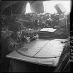 General D. M. Sutton, Winnipeg, Man., plotting gun range in dugout. 22 June 1944