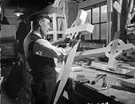 Chief Shipwright W. Harding making wooden crosses for naval graves, St. John's, Newfoundland, 28 October 1943. October 28, 1943.
