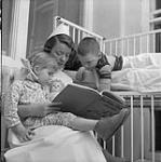 L'infirmière Merle Shields lit un conte aux enfants Wendy Le Brooy et Patrick O'Brien dans la section de pédiatrie de l'hôpital Royal Victoria. mars 1953