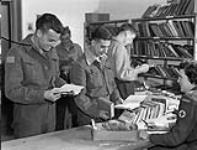 Patients using the library of No.1 Canadian General Hospital, R.C.A.M.C.. (Left to right): Ptes. R.J. Edwards, V.L.J. Sparkes, J. Godin, Gnr. V. Williams, Canadian Red Cross Worker Eleanor. 2 Apr. 1944