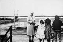 Mme Haggerty avec trois enfants (Inuit) se rendant à l'école, Yellowknife, T. N.-O., vers 1970 1970.