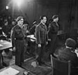 SS Brigadefuhrer Kurt Meyer standing in court with escorts Major Arthur Russel (left) and Captain Elton D. McPhail (right) 10 Dec. 1945