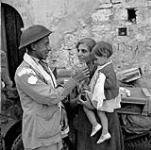 Trooper Ralph Catherall of The Calgary Regiment giving food to an Italian child, Volturara, Italy, 3 October 1943. October 3, 1943.