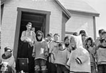 Le père Trinell avec des enfants inuits devant la mission catholique. Octobre 1951