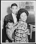 Jee-Kin enters Canada papoose-style with his mother, Kim Yin and father, Yung Chun Ku. The young family fled from China to Hong Kong and thence to Canada as part of 100 Chinese refugee families offered asylum Oct. 1962