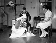 Nursing personnel of the Women¿s Royal Canadian Naval Service (W.R.C.N.S.) administering physiotherapy treatment, Halifax, Nova Scotia, Canada, July 1945. July 1945.