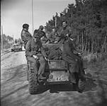 German and Hungarian prisoners riding on a 'Staghound' armoured car of the Manitoba Dragoons. 10 Apr. 1945