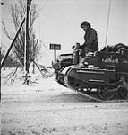 Bren gun carrier and soldier on road, passing sign reading Zetten. 20 Jan. 1945