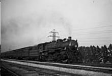 Right 3/4 front view of No. 16 4-6-2 Pacific locomotive of the Toronto Hamilton and Buffalo Railway leaving the Sunnyside station for Hamilton and Buffalo at twilight. 1947