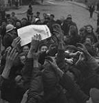 Civilians grasping a newspaper. 10 July. 1944