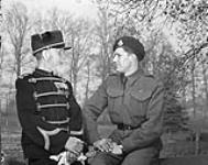 Trooper L.W. Goss of the 8th Princess Louise's (New Brunswick) Hussars talking with a retired Dutch soldier as they sit on an old cannon which bombarded Algiers in 1816. Arnhem, Netherlands, 16 April 1945 Apri1 16, 1945.
