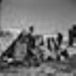Une femme inuite met des bottes en peau de phoque à sécher devant sa tente à Pangnirtung. [Aasivak Evic, femme d'Angmarlik et grand mère de la famille Evic, en train de faire sécher des " kamiks ".  On aperçoit le Mont Duval en arrière-plan]. Août 1946