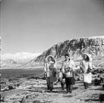 Femmes [Femme au milieu est Evee Anilniliak] et un enfant inuits marchant sur la rive à Pangnirtung  août 1946.
