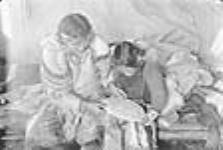 (Femme autochtone coud à sa maison avec sa fille.) [Iggi (à gauche) montre à Utuqayuak (à droite) comment fabriquer des " kamiks ".] 1949