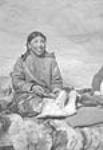 (Femme inuite nettoyant une peau à l'aide d'un ulu pour en faire un vêtement. Padlei, T.N.-O., 1949-1950.) [Kialik, fille d'Ikualak et d'Atuat, fabriquant des vêtements en peau de caribou.] 1949-1950