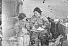 (Femme inuite nettoyant une peau avec son enfant. Padlei, T.N.-O., 1949-1950.) [La mère de Kinalik, Paalak, lui montre comment faire des patrons.] 1949-1950