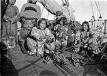 William Harold Grant with head man's two wives and child on board C.G.S. ARCTIC. [Standing: Ulaajuk (left) and Nutaraarjuk (right). Seated, left to right: Qulittalik, William H. Grant holding Akpaliapik and Puttiuq. Qulittalik and Puttiuq were the two wives of Takijualuk. This photograph was taken on board the C.G.S. "Arctic".]. 2 Sept. 1922