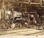 Locomotive 209 `Trevithick', in the Grand Trunk Railway erecting shops. F.H. Trevithick, engineer with the GTR and son of the inventor of the railway locomotive, standing by the forward driving wheel. 1858