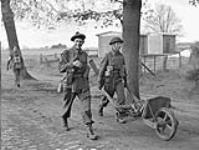 Infantrymen of the Queen's Own Cameron Highlanders of Canada hauling surplus kit in a wheelbarrow near Oldenburg, Germany.
