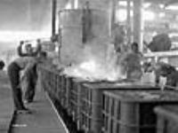 Des ouvriers manoeuvrent une poche de coulée utilisée pour verser des métaux fondus dans les moules de bombes à l'usine Cherrier. mai 1941