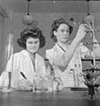 Female laboratory workers Isobel Johnson of Webb, Sask., and Cathrine Moran of Vancouver, B.C., test gases in the Polymer Corporation of Canada analytical laboratories. Oct. 1943