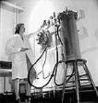 Une employée règle le robinet d'un appareil utilisé pour enlever les impuretés lors de la fabrication de pénicilline aux laboratoires Connaught. mai 1944