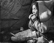 Mrs. Duval, a blind Inuit woman, using her tongue to thread a needle. August 1946