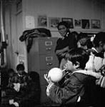 Young boy blowing up a balloon during the dance held at the Cape Dorset (Kinngait) Federal Hostel, Nunavut, August 1961  August 1961.