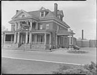 Exterior view of the Standish Hall Hotel, Hull, Quebec, with owner J.P. Maloney in foreground  ca. 1942-1951
