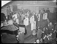 View of local musicians, "The Paul Herbert Band" performing at the Standish Hotel.  Members of the airforce and army dancing, with two navy MP's watching. 1944.