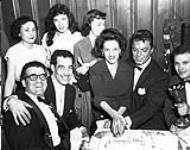 Singer Guy Mitchell (second from right) cutting a birthday cake, with guests at the Standish Hotel's "Happy Birthday Show" being recorded by radio station CKOY. ca. 1950.