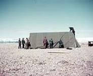 Straightening canvas cover over Atwell shelter hut E.P.I. (Electronic Position Indicator) Cape Fisher station site. July, 1955