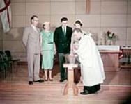 Protestant Chaplain W.W. Levatte christening a baby in the Church of the Redeemer, Shannon Park Dartmouth N.S. 1957