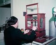 Royal Canadian Naval Hospital Laboratory, Mary Sellers weighs chemical reagent. 15-Jul-57