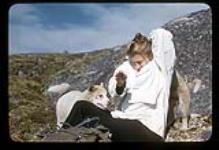Barbara Hinds sitting outside with husky pups. [between June 17-October 31, 1960]