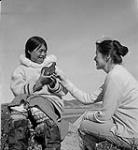 [Alma Houston (right) and a woman (left) [Qaunaq Mikkigak} holding a bird sculpture, Kinngait, Nunavut]  [between 1956-1960]