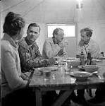 [Barbara Hinds and Mackenzie Porter socialising with people around a table]. [between 1956-1960]