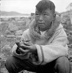 [Teevee holding a miniature seal, Kinngait, Nunavut]. [between 1956-1960]