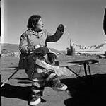 [Woman sewing while seated on a bench, Iqaluit, Nunavut]. [between 1956-1960]