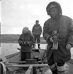 [Three men standing in a boat]. [between 1956-1960]